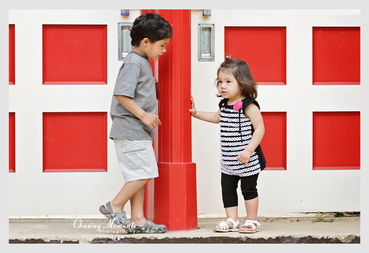 Portrait of brother and sister next to a colorful red and white door