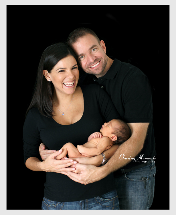 mom, dad and baby girl - family portrait with a newborn on black background, studio