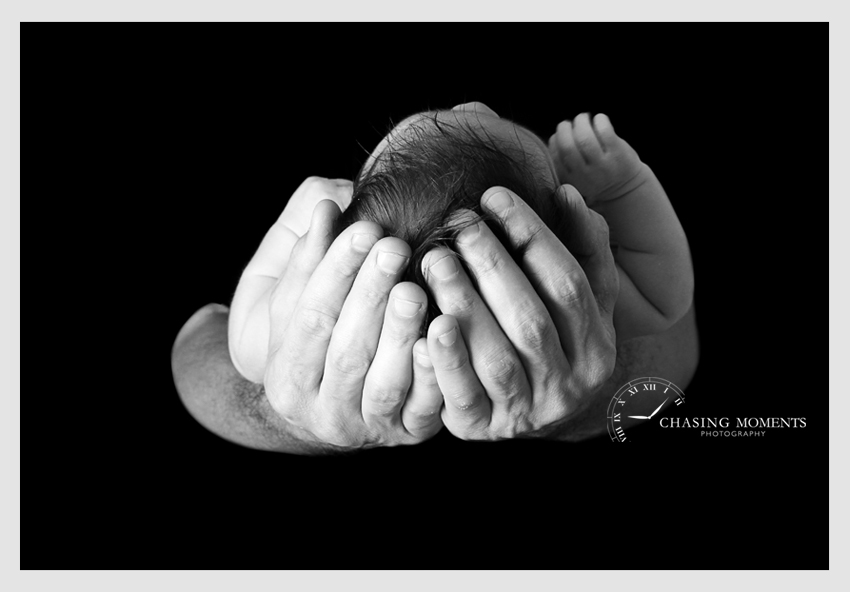 baby in dad's hands black and white