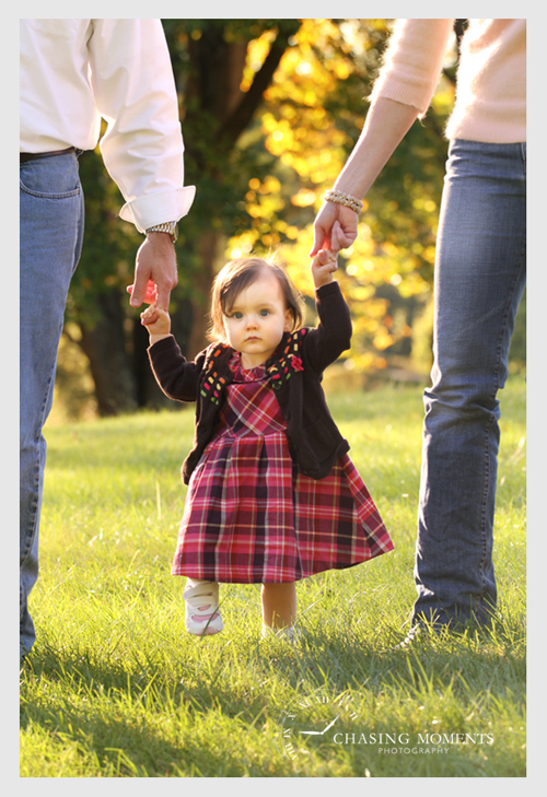 one year old baby girl walking holding parents hands at meadowlark gardens va