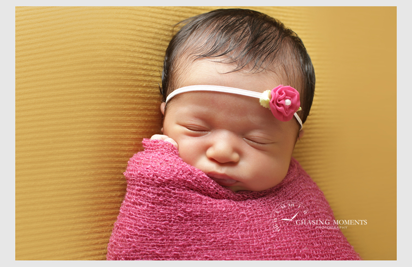newborn baby girl with pink rose headband swaddled